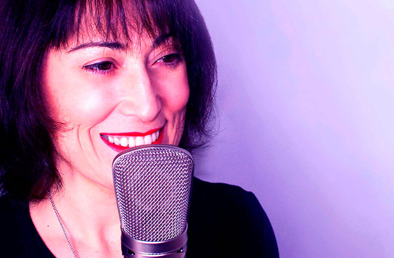 Lores Marcó sonriendo frente a un micrófono de estudio